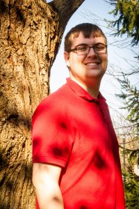 Dylan Green stands next to a tree smiling